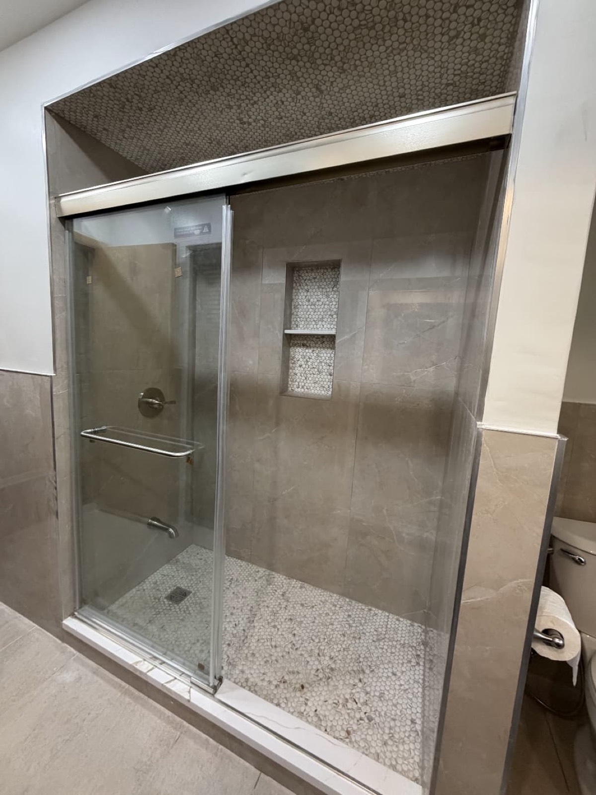 Gray tile shower with glass door and mosaic floor