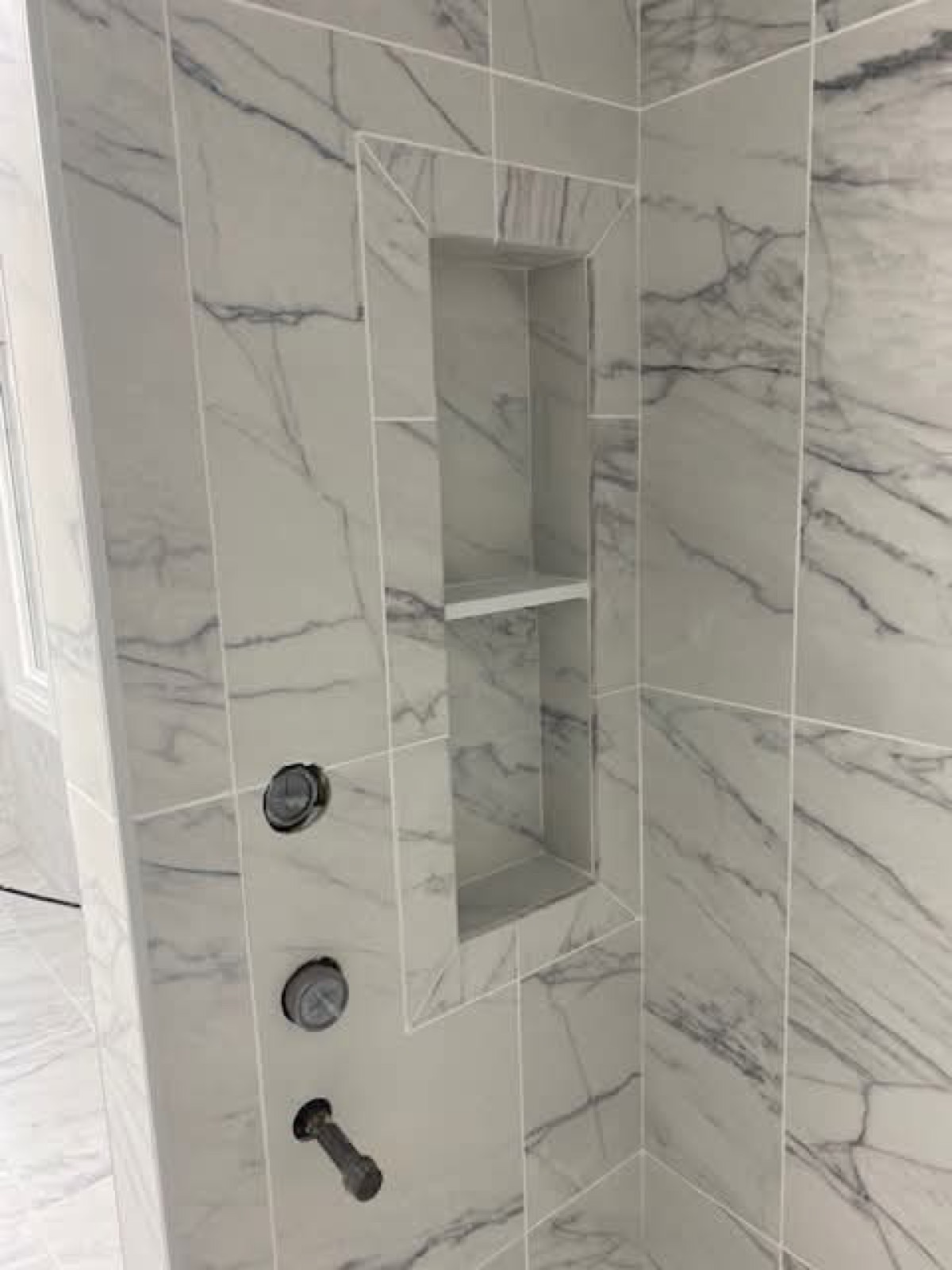 Marble tile shower niche with black fixtures