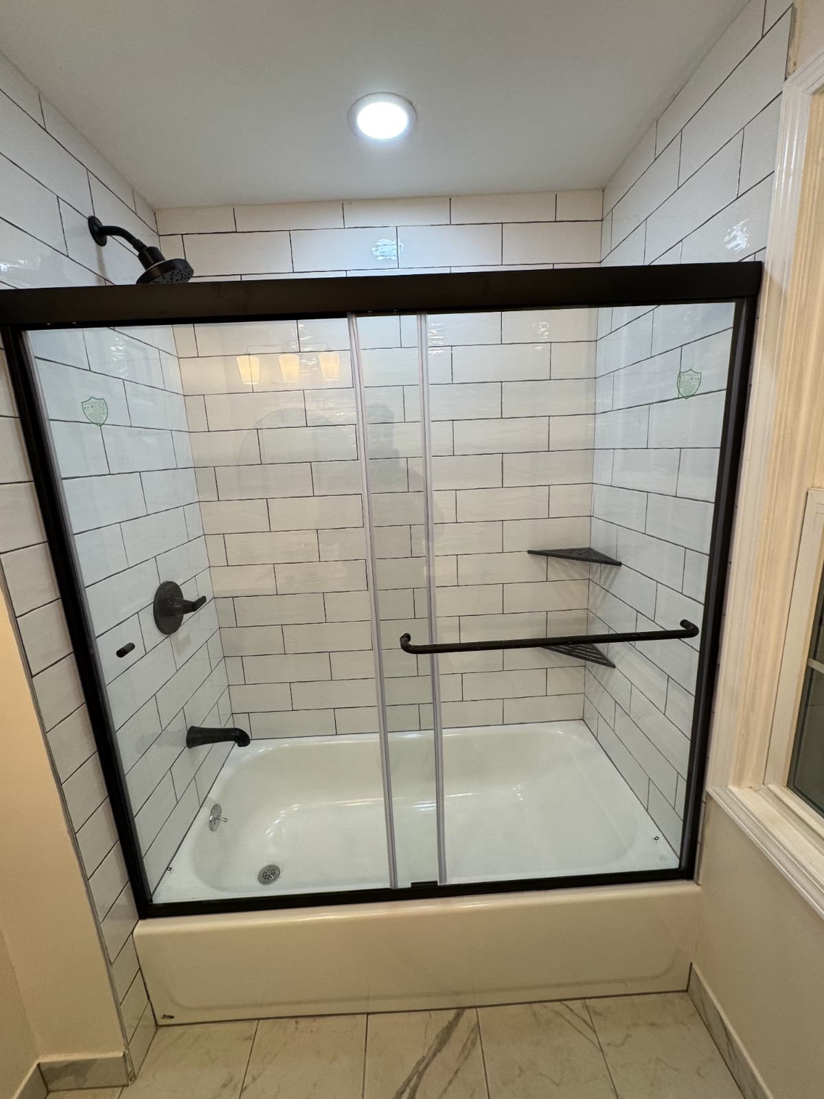 White subway-tile tub and shower with black-frame glass doors